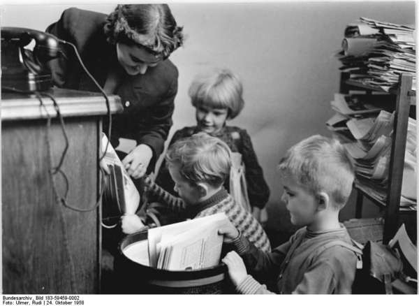 Woman with children, who are collecting old newspapers