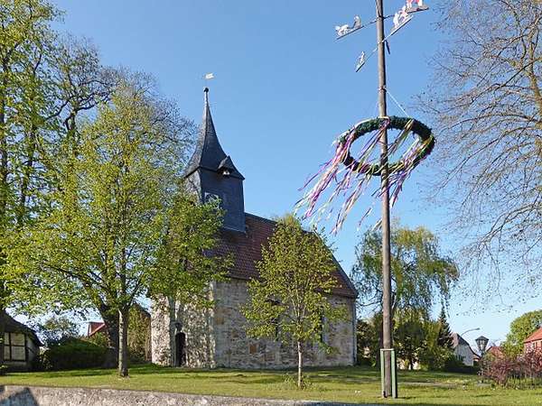 Photo of a maypole in front of an old church.