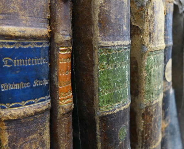 Spines of old German church books on a shelf.