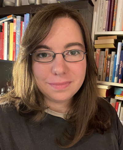 Photo of a woman with glasses in front of a bookshelf